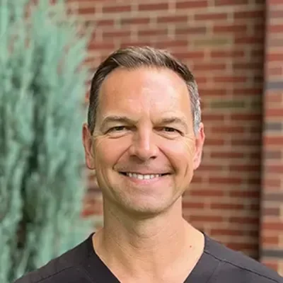 Shawn Finn smiling in front of a brick wall.
